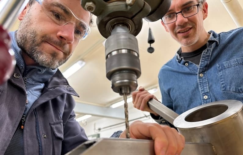 Drei Freunde arbeiten an der Kaffeeröstmaschine